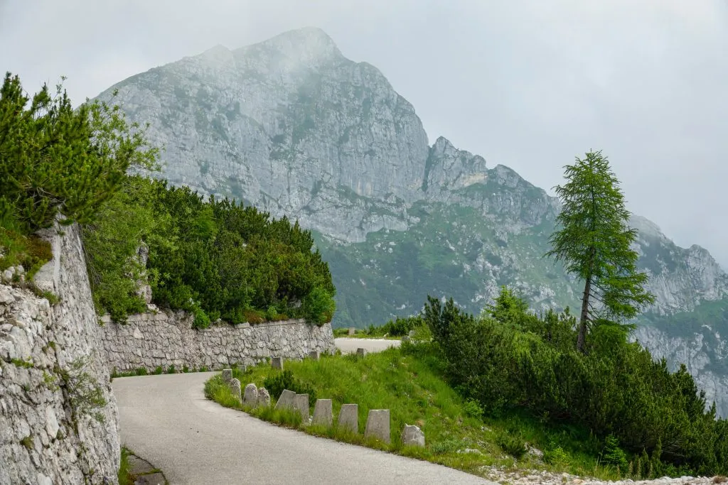 Naturskønne klippebjerge med udsigt over en tom asfaltvej, der løber tværs over De Julianske Alper.